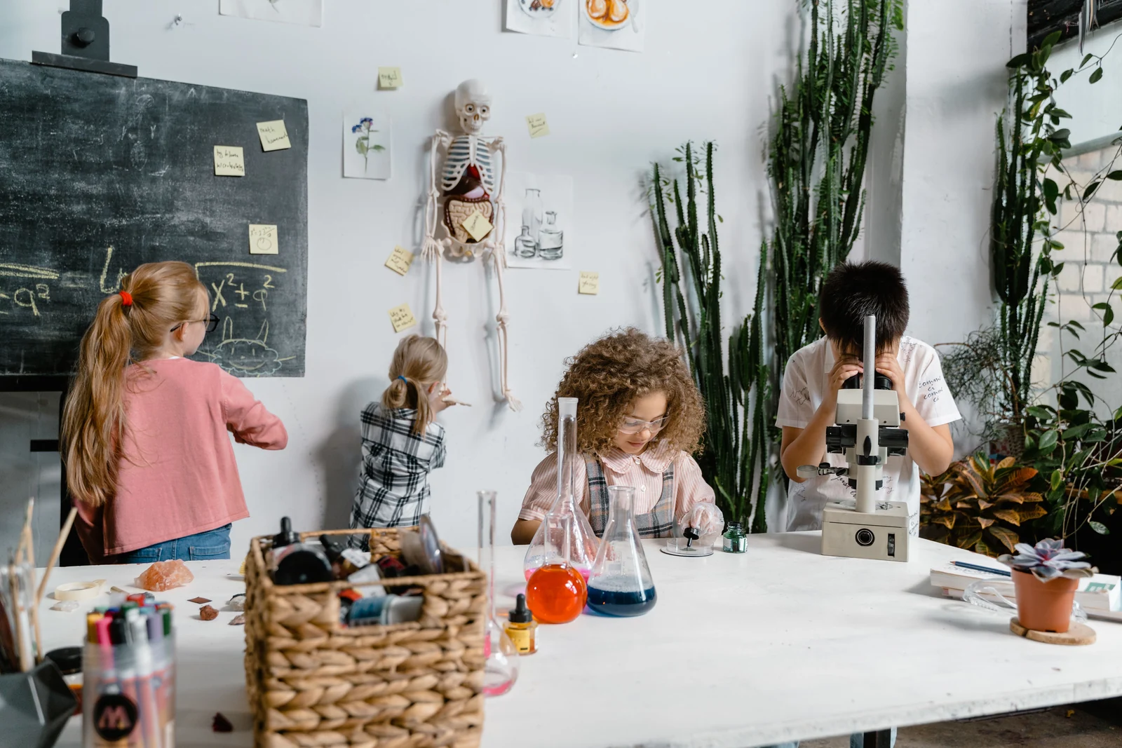 Niños realizando un experimento con matraces y microscopio en un aula